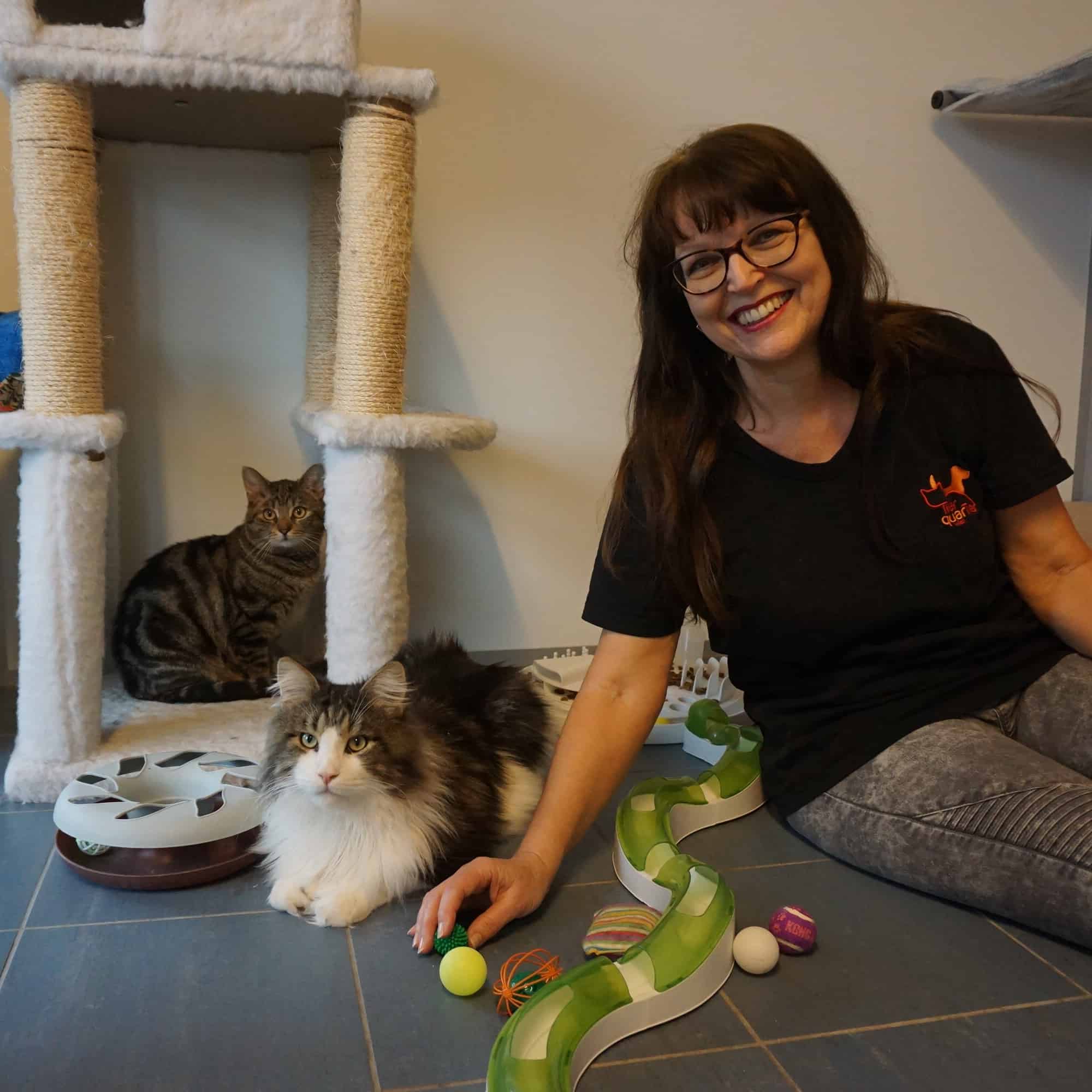 Eine Frau sitzt auf dem Boden und streichelt eine Katze.